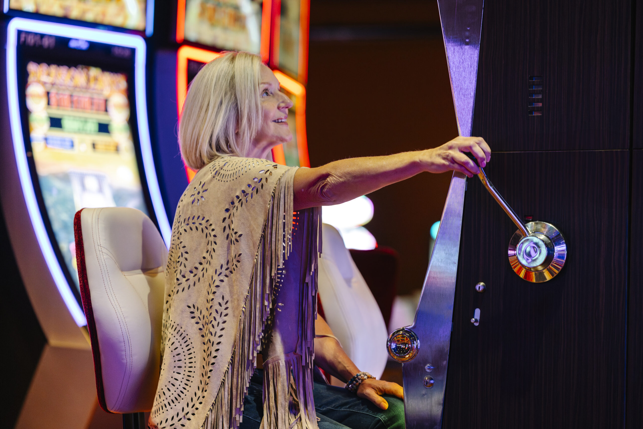 A woman in a shawl pulls the lever on a slot machine at The Casino