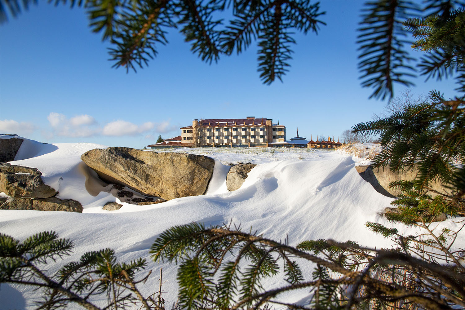 a hotel is pictured in the distance with snow covered rocks in the foreground